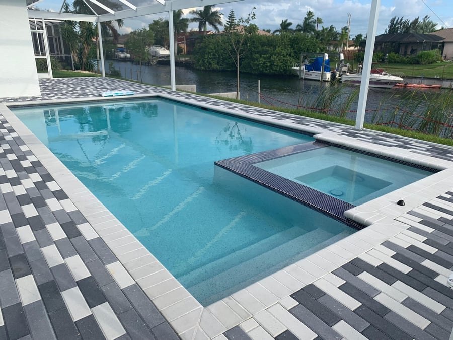Checkered paver deck around a canal front pool and spa