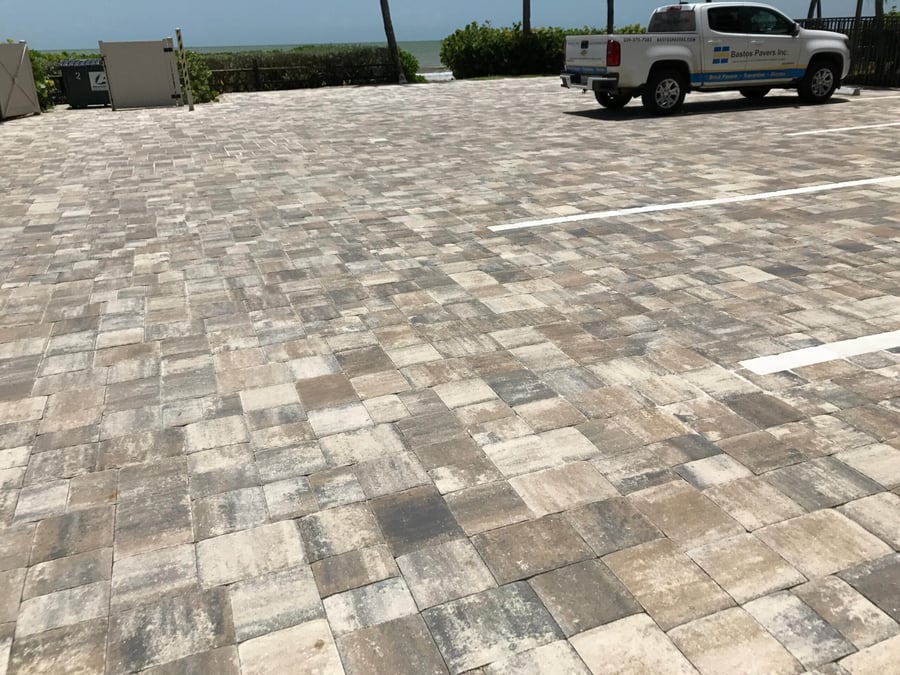Gulf-front parking area in tumbled gray and tan pavers with Bastos truck