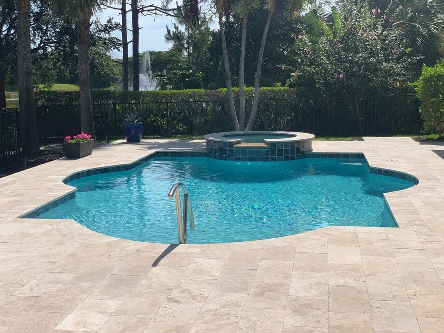 Travertine pool deck with round spa overlooking a lake fountain
