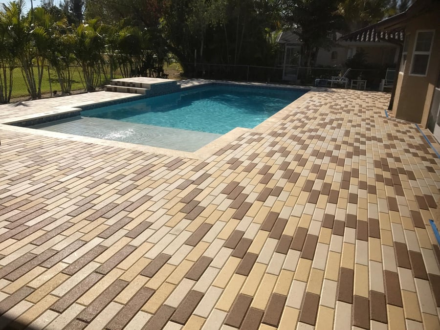 Multicolor brick paver pool deck in herringbone pattern