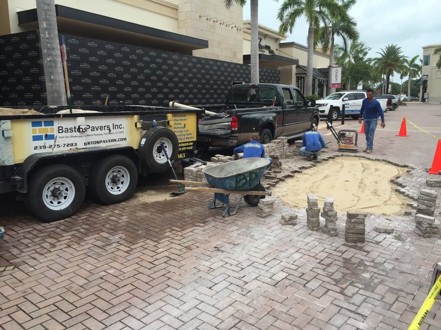 Bastos trailer and crew repairing plaza pavers in a coned work zone