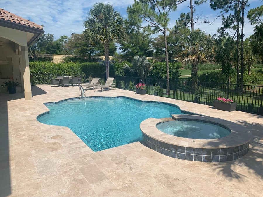 Travertine deck around a freeform pool and round spa
