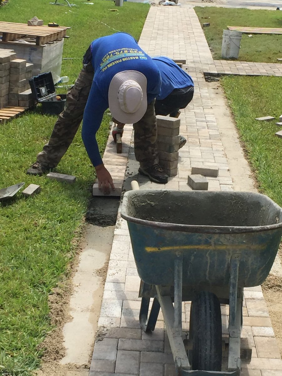 Crew laying paver walkway with concrete edge restraint