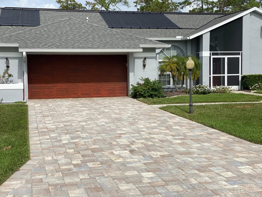 Tan paver driveway leading to a two car garage
