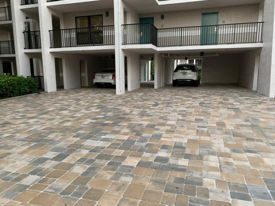 Condominium carport court paved in tumbled gray and tan pavers