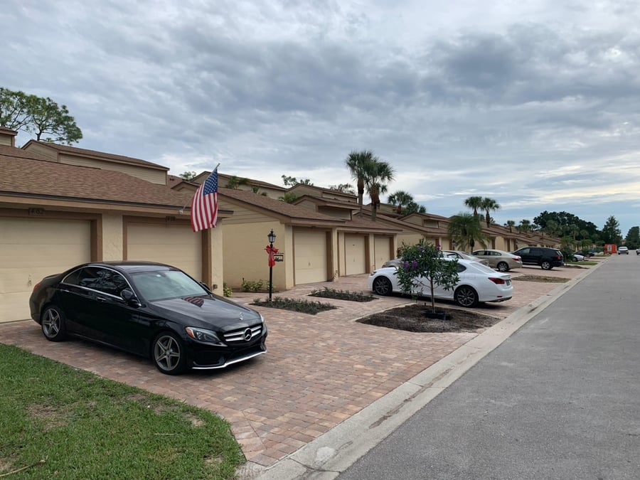 Paver parking aprons in front of villa garages along a community street