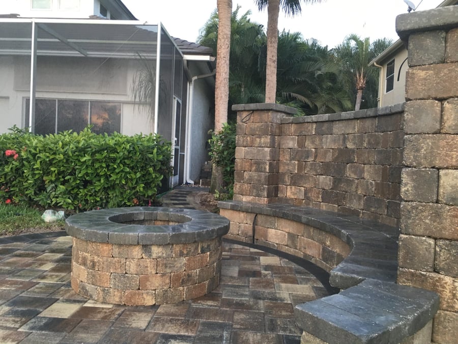 Round paver fire pit with a curved bench wall and privacy wall