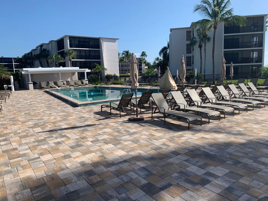 Beach condominium pool deck in blended pavers with rows of loungers