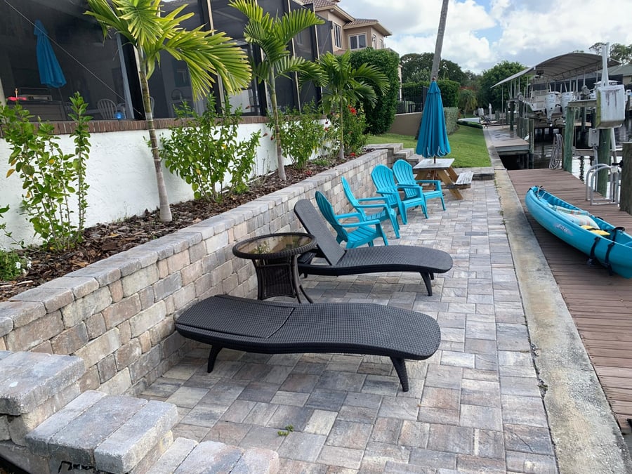 Canal side paver walkway with seat wall and lounge chairs