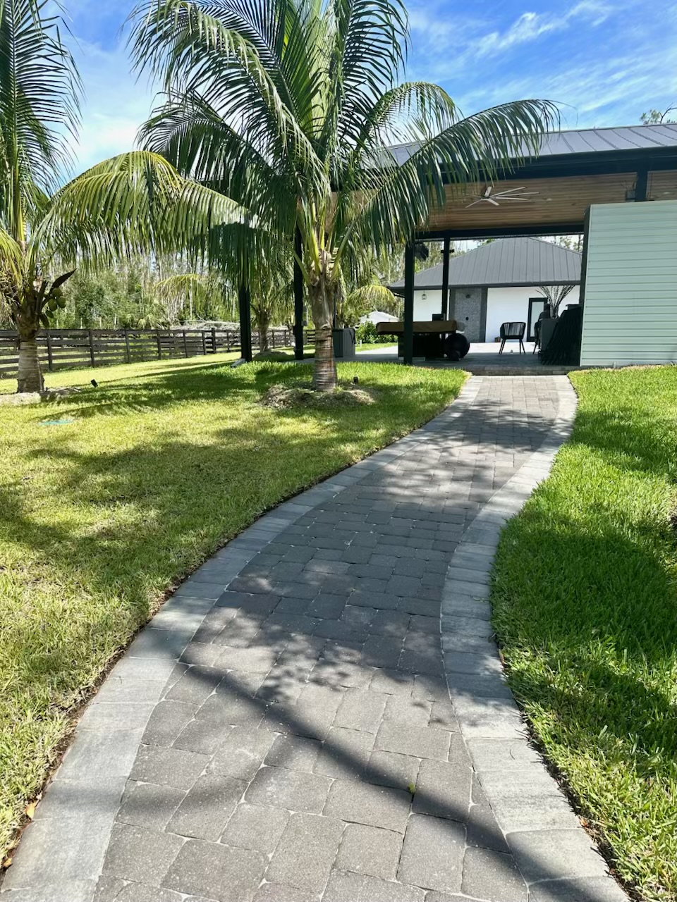 Curved paver walkway through a lawn toward a covered pavilion