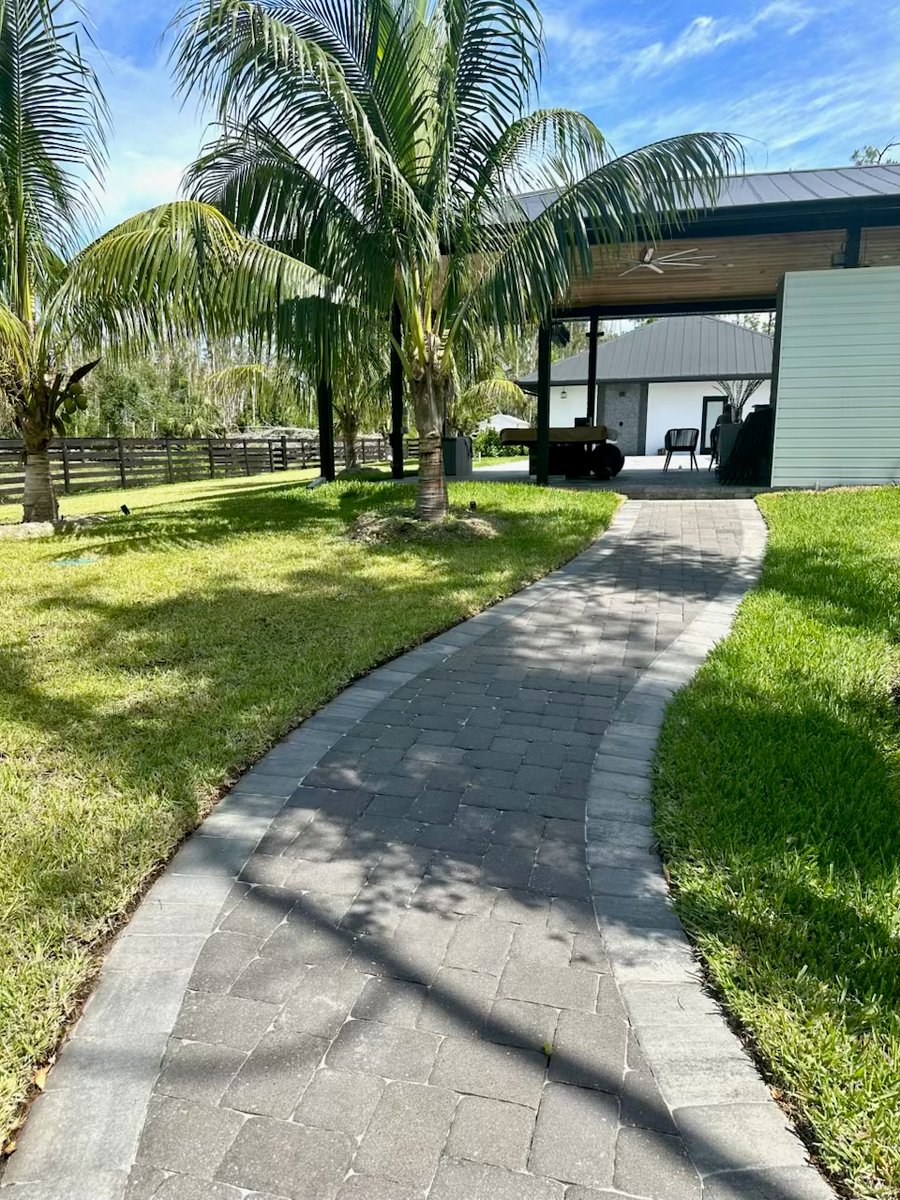 Curved paver walkway through a lawn toward a covered pavilion