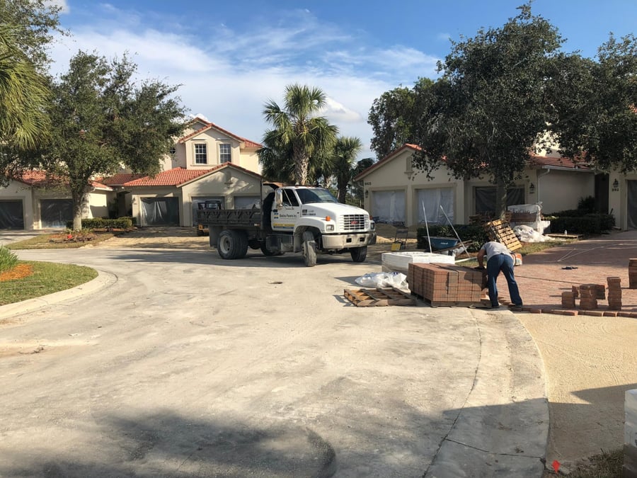 Crew unloading brick paver pallets for a coach home driveway project