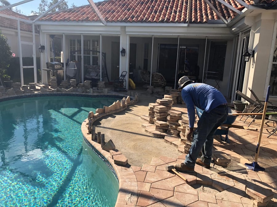 Crew remodeling a pool deck with new pavers