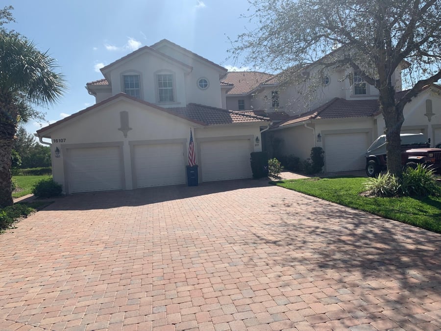 Wide brick paver driveway serving a triple-garage coach home
