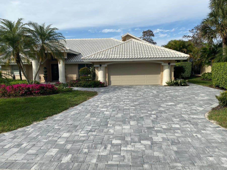 Gray ashlar pattern paver driveway leading to a two car garage