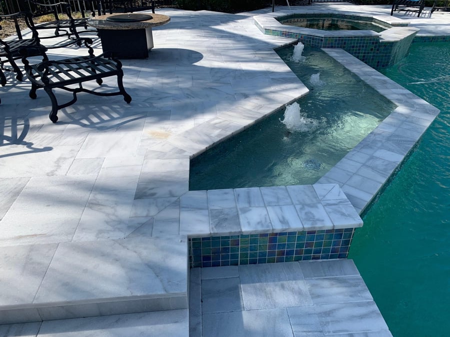 White marble pool deck with fire table seating