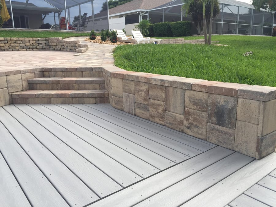Paver retaining wall with steps beside a composite deck