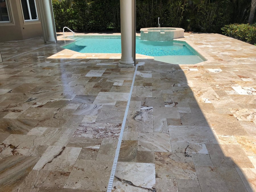 Polished French pattern travertine lanai around a pool and spa