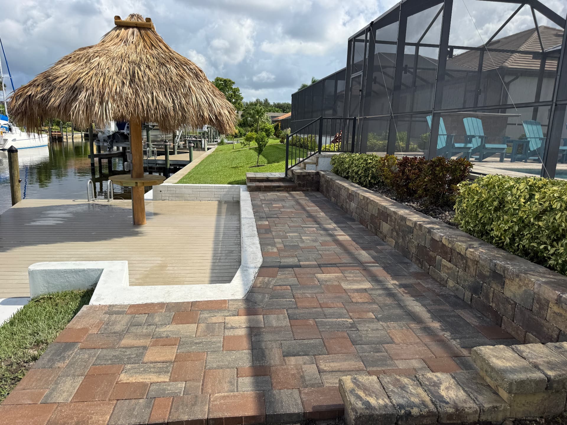 Paver walkway along a canal with retaining wall and tiki hut