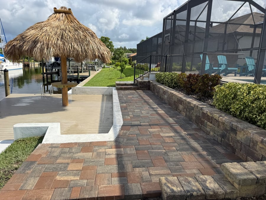 Paver walkway along a canal with retaining wall and tiki hut