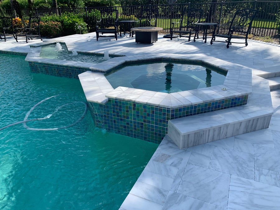 Marble deck with octagonal spa and glass tile spillover