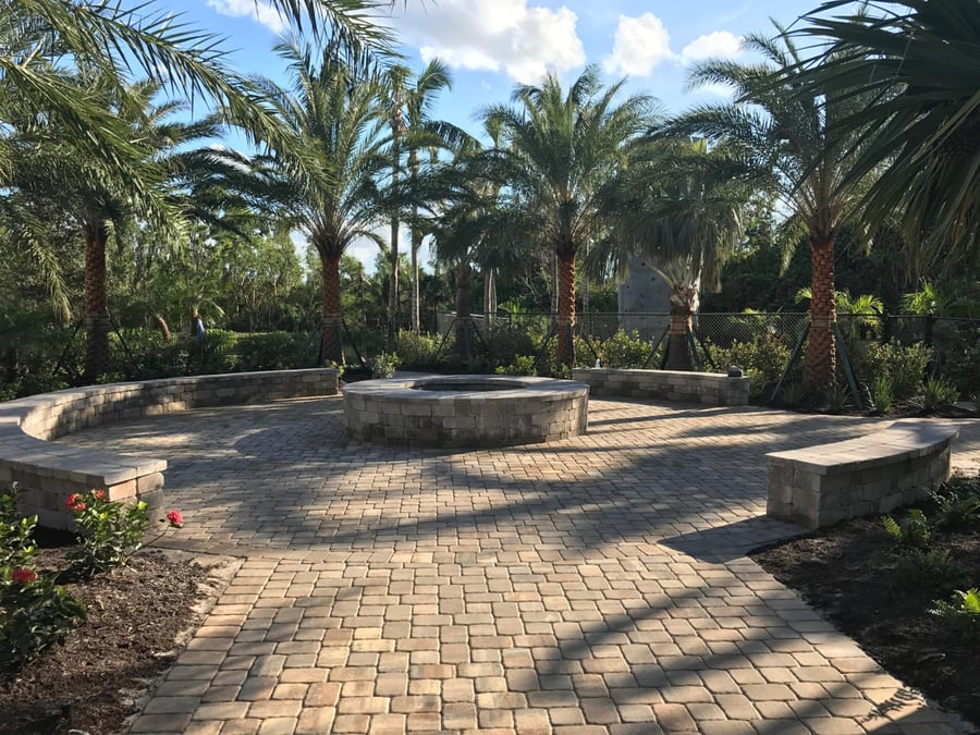 Amenity fire pit surrounded by curved paver seat walls and palms
