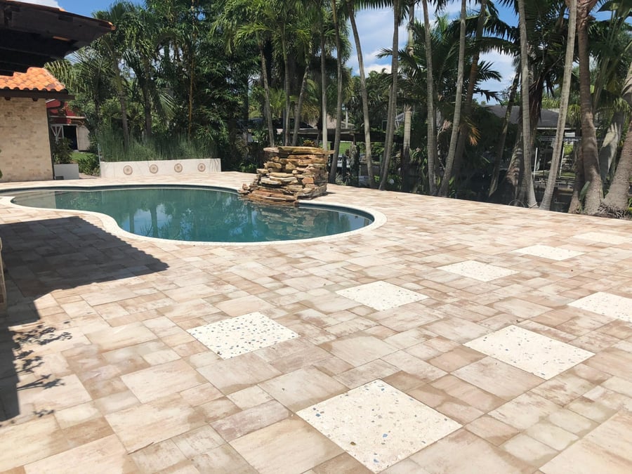 Pool deck with terrazzo accent tiles and stacked stone water feature