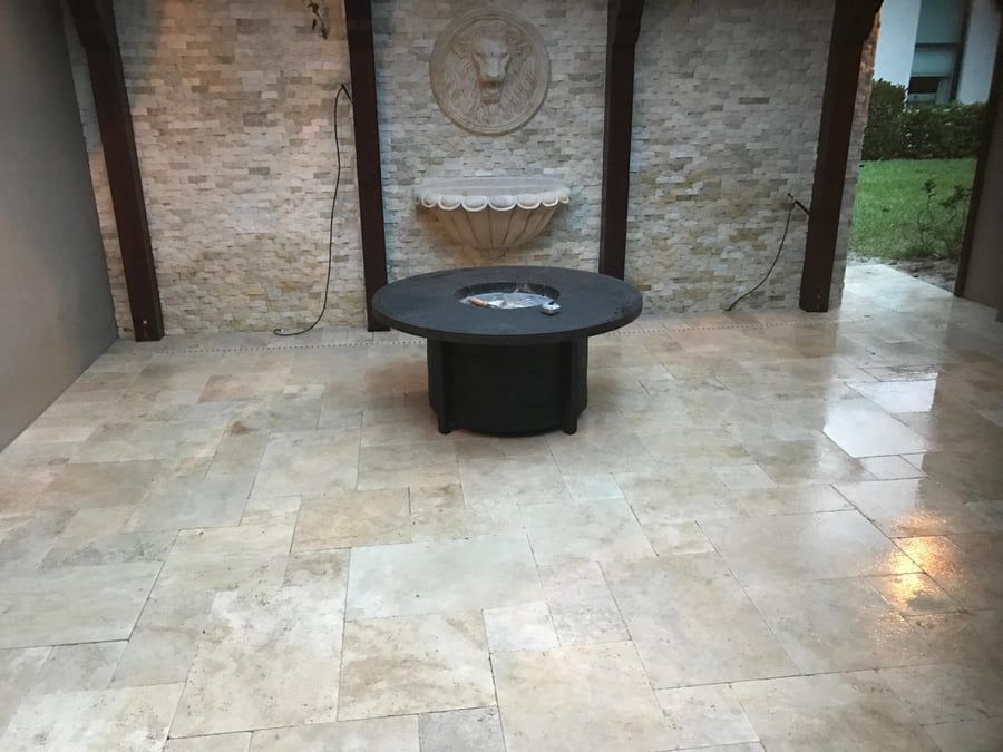 Travertine courtyard with a round fire table and stone fountain wall