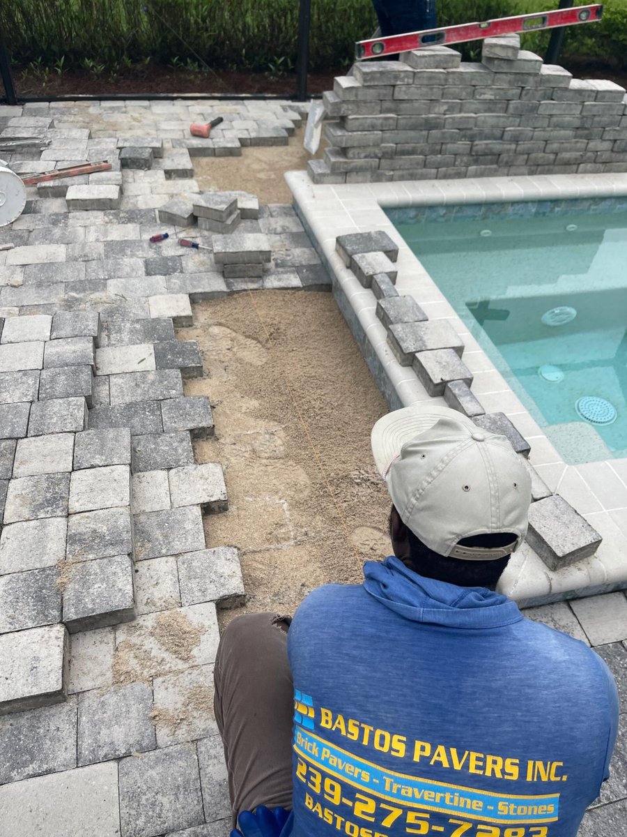 Crew installing paver deck and wall around a new spa