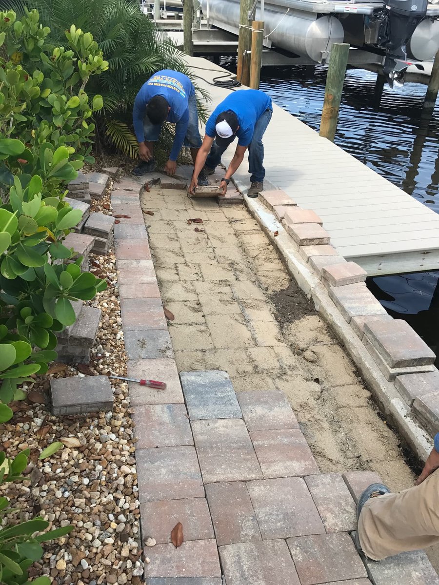 Crew resetting pavers along a waterfront dock walkway