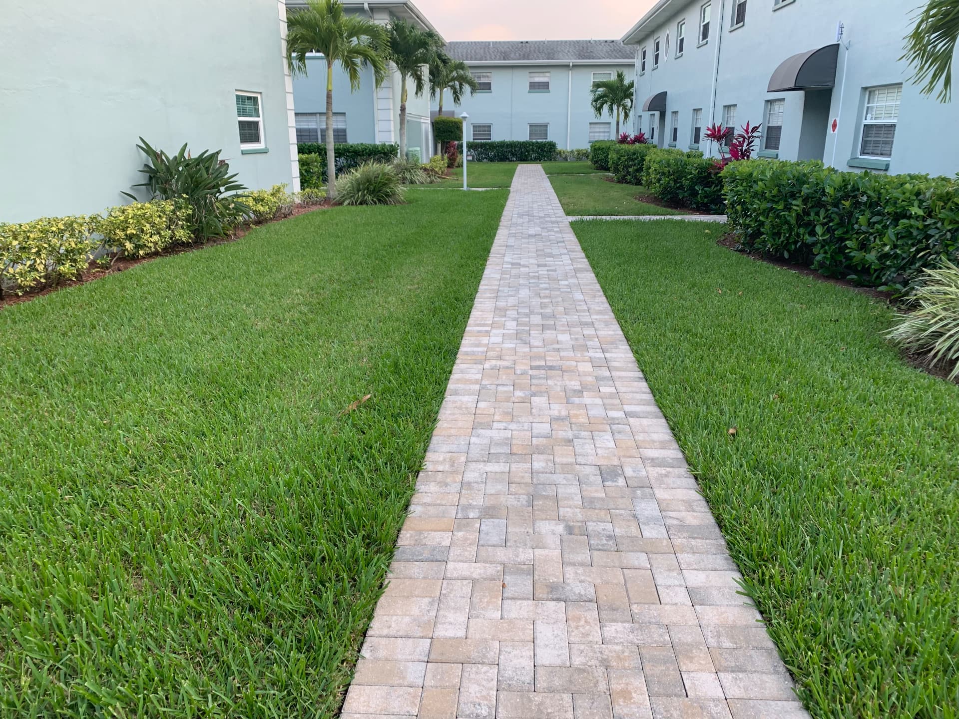 Straight paver walkway between lawns at a condominium community