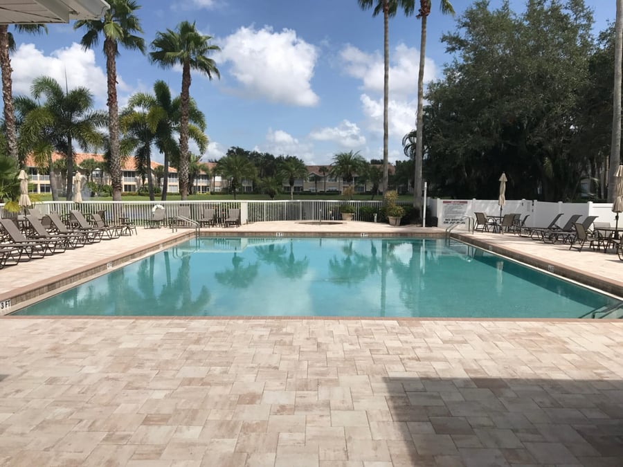 Community pool deck paved in travertine with lounge seating