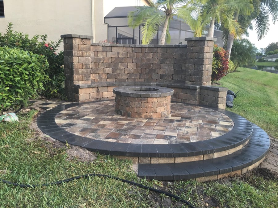 Round paver patio with fire pit and curved seat wall
