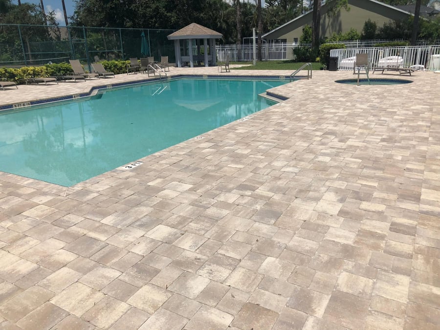 Community pool and spa surrounded by tumbled paver decking