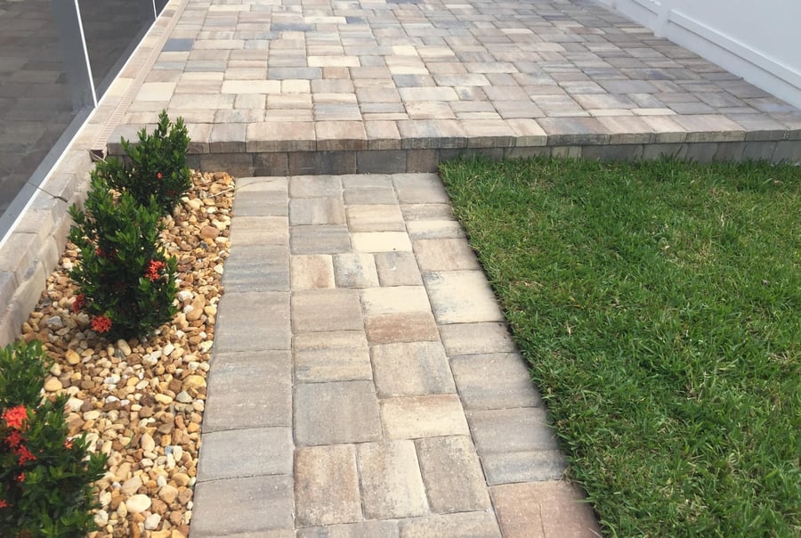 Raised paver patio with a step down walkway and stone border