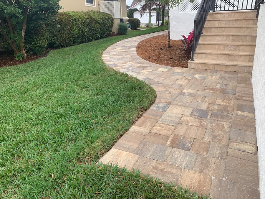 Curved paver walkway passing a side yard toward travertine steps