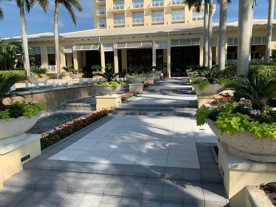 Resort entry walkway with fountain, planters and large-format stone paving