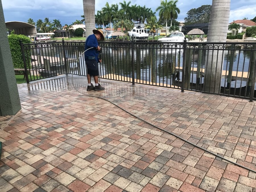 Pressure washing a waterfront paver patio by a canal