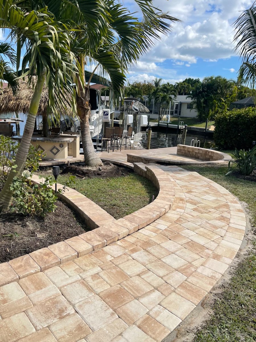 Curved paver walkway wrapping a planting bed beside a waterfront patio