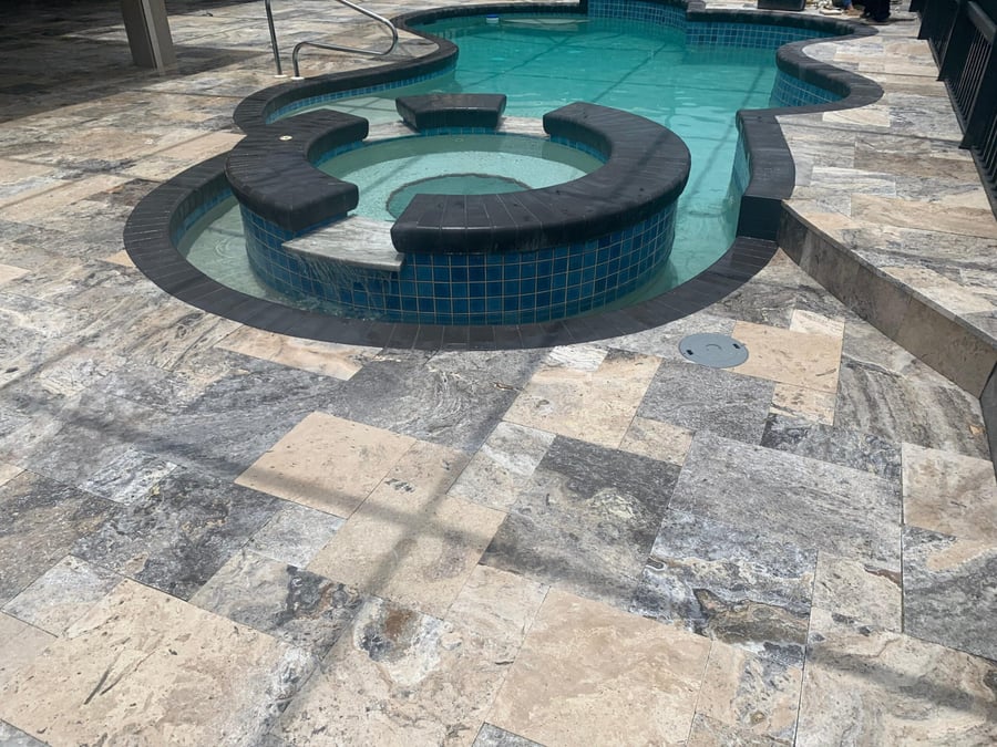 Silver travertine deck with curved spa bench and dark coping