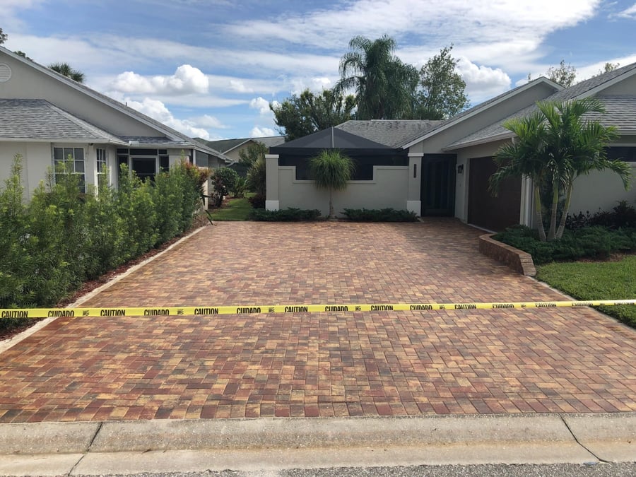 Freshly finished red blend paver driveway with caution tape