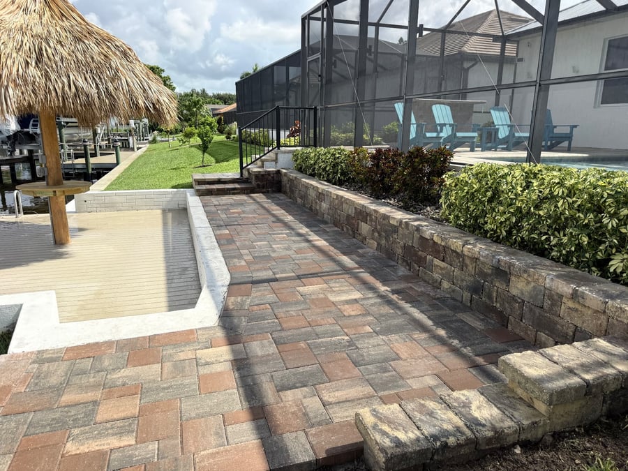 Herringbone paver patio walkway with retaining wall and pool screen enclosure