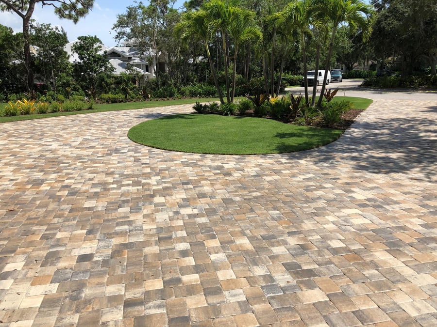 Circular tumbled paver driveway around a landscaped grass island