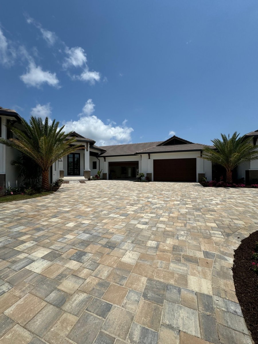 Wide estate courtyard paver driveway between palms