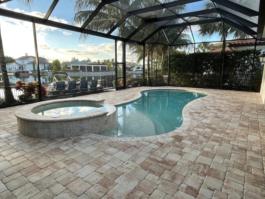 Screened lanai pool deck overlooking a lake at sunset