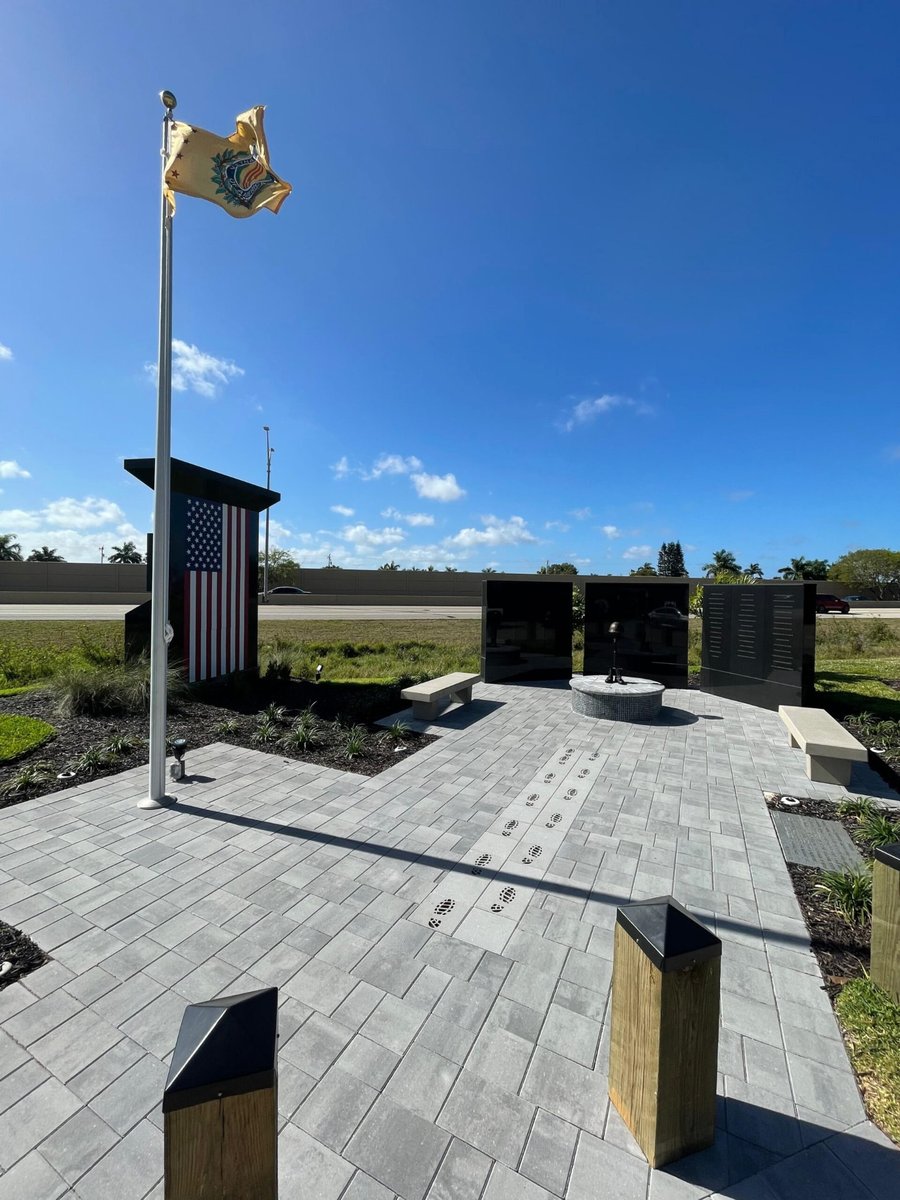 Veterans memorial plaza in gray plank pavers with flagpole and granite walls