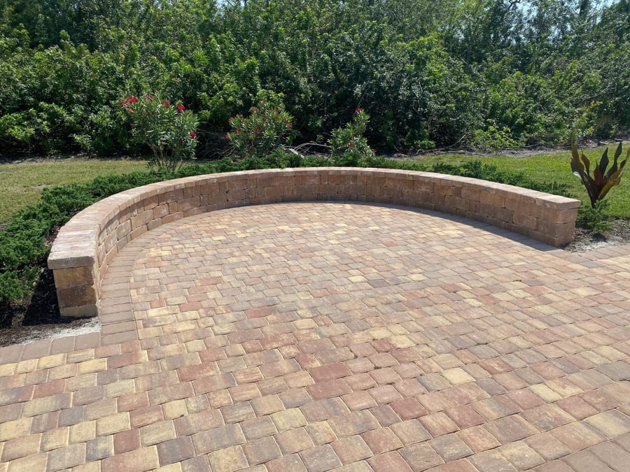Curved paver seat wall around a tumbled brick patio