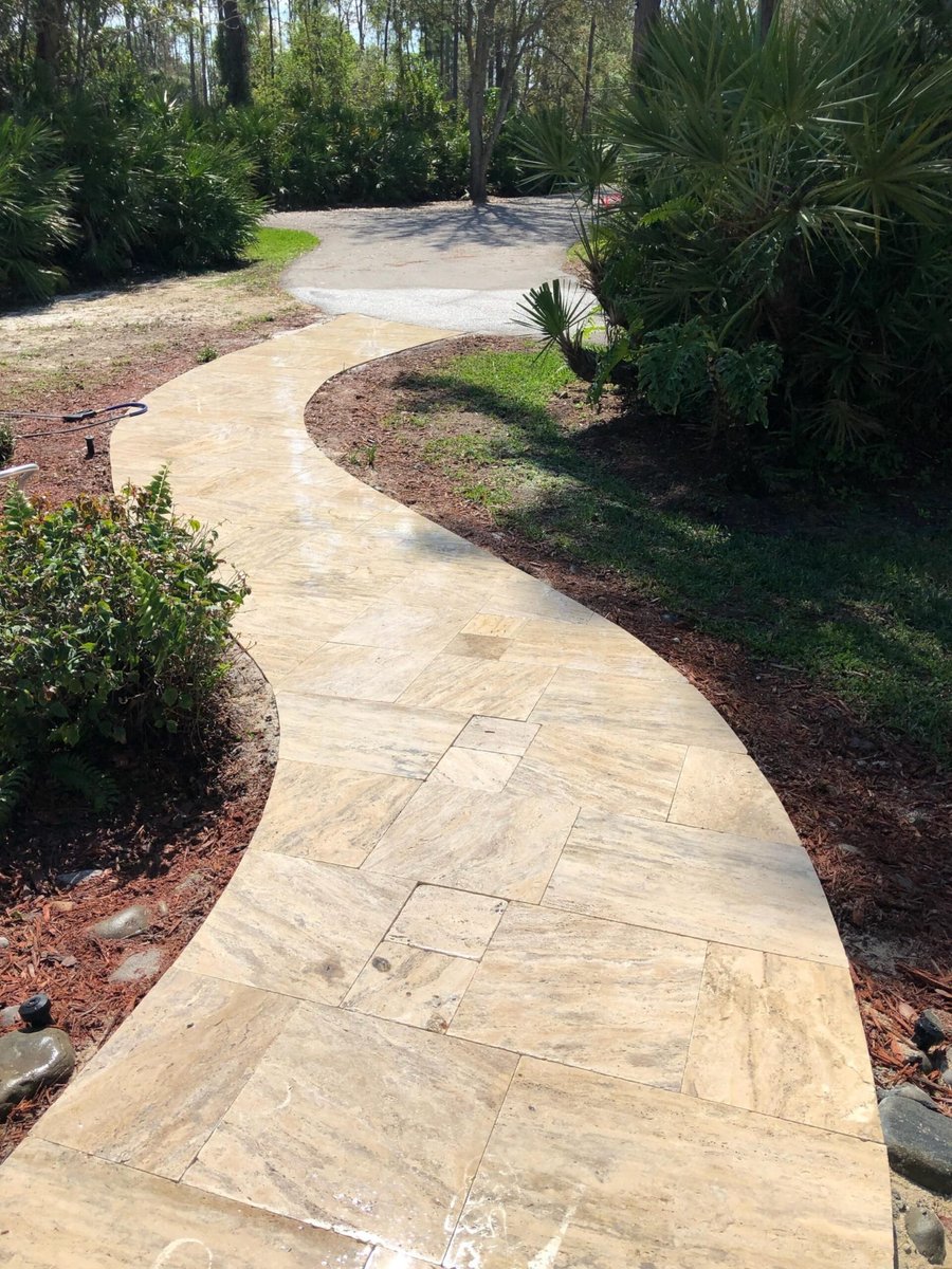 Winding travertine walkway through tropical landscaping