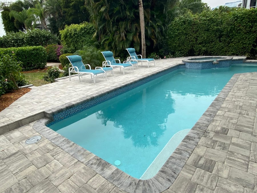 Paver pool deck with lounge chairs and spillover spa