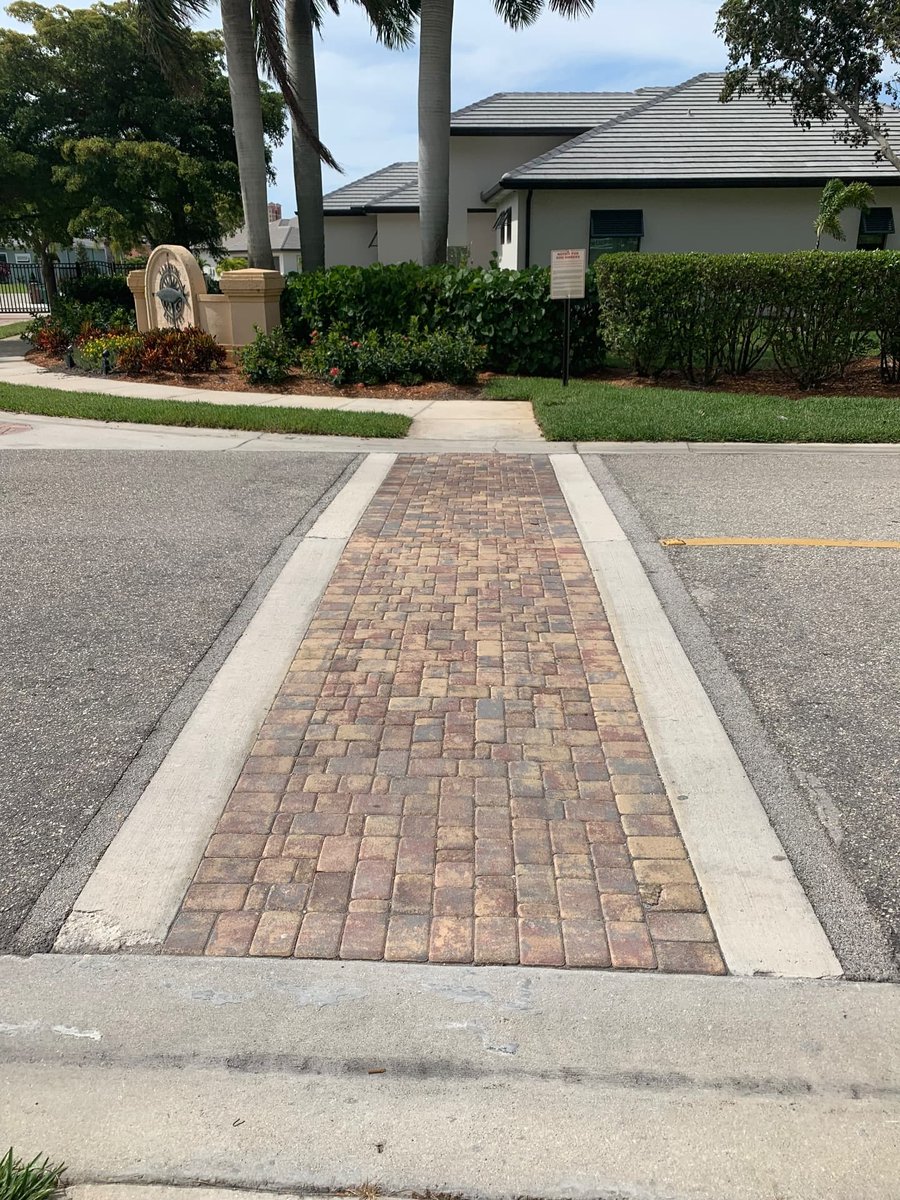 Paver crosswalk crossing a community roadway with monument sign